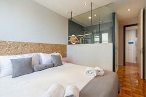 Una habitación de hotel moderna con una cama grande, un espejo y piso de madera.
