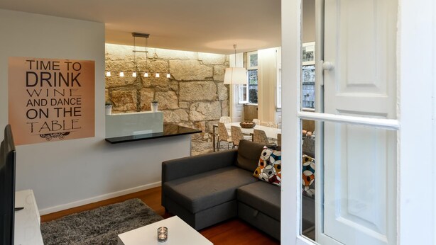 Un salon chaleureux avec un mur en pierre, une table à manger et un canapé.
