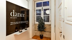 Un couloir orné d’une enseigne décorative sur laquelle on peut lire « dansez à travers la vie », ainsi que d’une citation de Wayne Dyer. Une petite plante en pot et trois lanternes allumées sont posées sur une étagère.