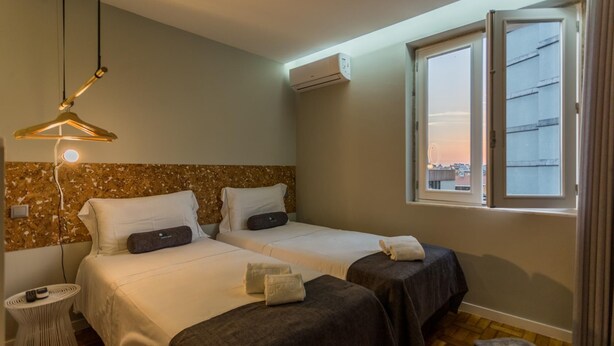 Hotelkamer met twee bedden, een hanglamp, een airconditioning en een raam met uitzicht op de stad.