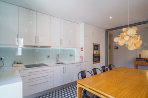A modern kitchen with white cabinets, a stainless steel sink, and a wooden dining table.