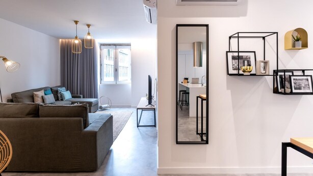 A modern living room with a grey sofa, a dining area with a small table, and a kitchen visible through an open door. - Feel Porto Pinot Townhouse (Porto)