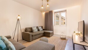 A modern living room with a sectional sofa, a floor lamp, a TV stand, and a large window with curtains. - Feel Porto Pinot Townhouse (Porto)