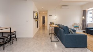 A modern living room with a blue sofa, a wooden dining table with chairs, and a small side table. - Feel Porto Bacchus Townhouse (Porto)