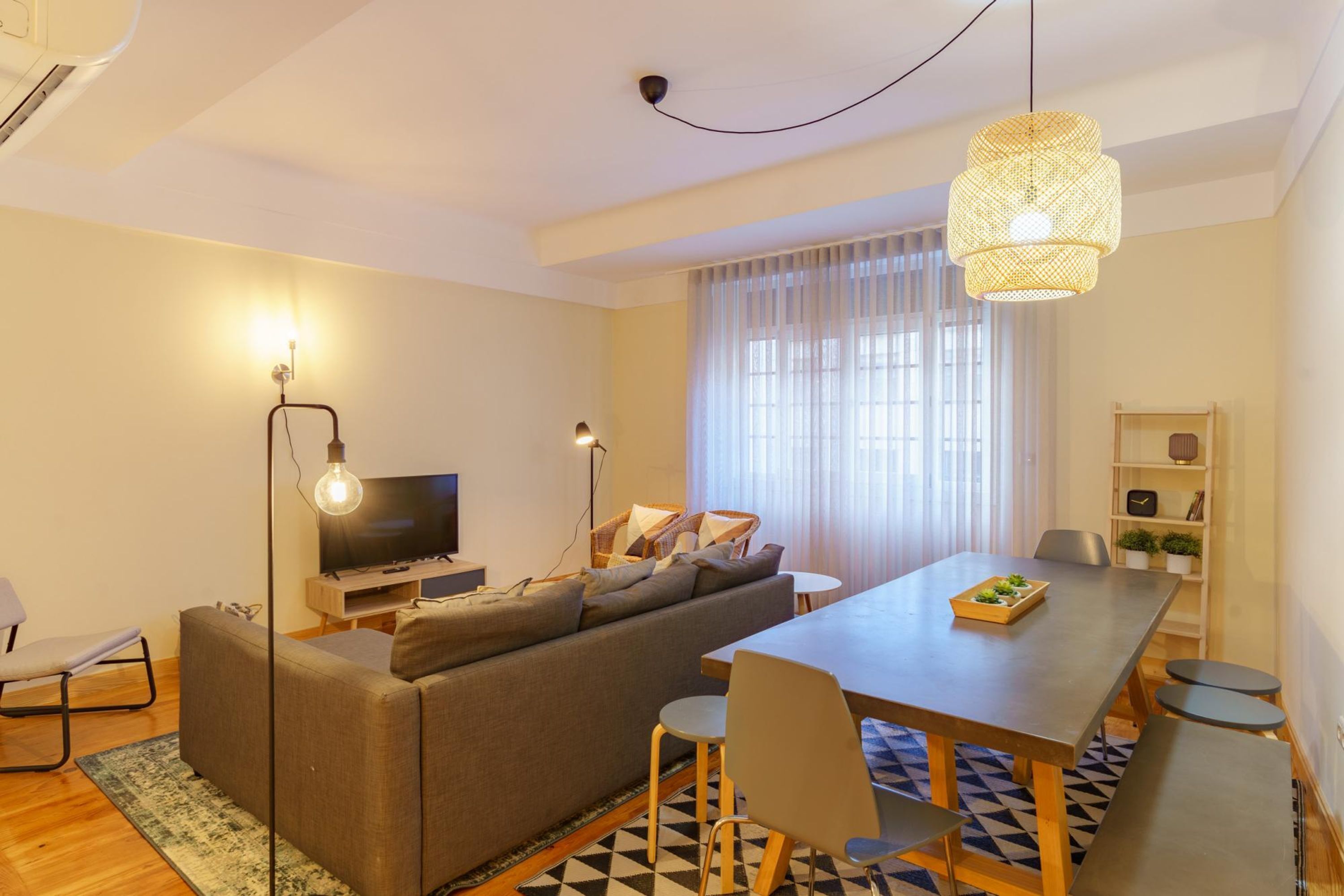 Una sala de estar moderna con sofá, televisor, mesa de comedor y sillas.