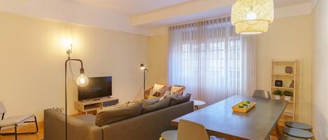 Una sala de estar moderna con sofá, televisor, mesa de comedor y sillas.