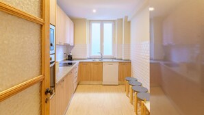 A modern kitchen with wooden cabinets, a dishwasher, a sink, and a window. - Feel Porto Downtown Woods Flat (Porto)
