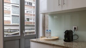 A kitchen with a granite countertop, a coffee maker, and two cartons of milk. - Feel Corporate Housing Marqu s I (Porto)