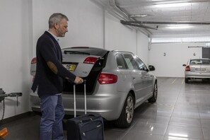 A man with a suitcase in a parking garage.
