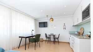 A modern kitchen with a microwave, sink, and countertop. There is a dining area with a table and chairs. - Feel Corporate Housing Marqu s IV (Porto)