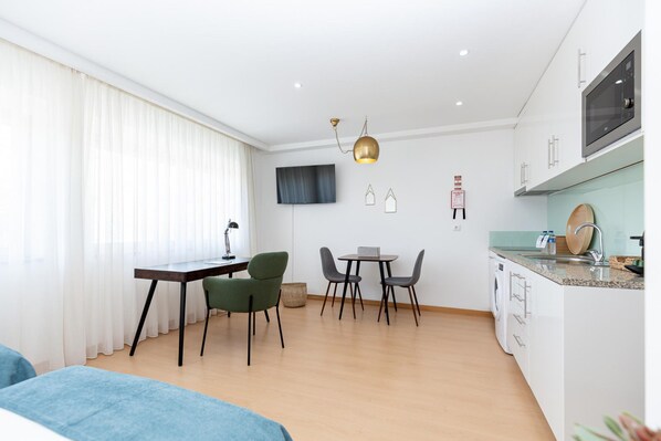 A modern kitchen with a microwave, sink, and countertop. There is a dining area with a table and chairs. - Feel Corporate Housing Marqu s IV (Porto)