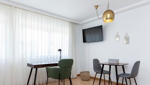 A dining area with a table and chairs, a television mounted on the wall, and a hanging light fixture. - Feel Corporate Housing Marqu s IV (Porto)