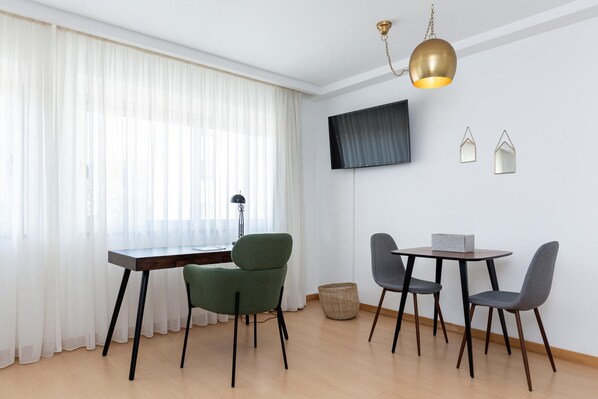 A dining area with a table and chairs, a television mounted on the wall, and a hanging light fixture. - Feel Corporate Housing Marqu s IV (Porto)