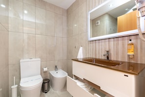 Un baño moderno con inodoro, bidé, tocador con lavabo y espejo.