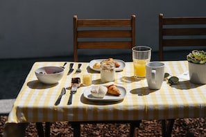 Una mesa dispuesta con artículos para el desayuno, incluyendo cruasanes, un tazón de bayas, un vaso de jugo de naranja y una jarra de leche.