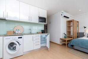 Una cocina compacta con lavadora integrada, microondas y un mueble de madera.