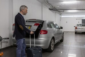 Un hombre con una maleta en un estacionamiento.