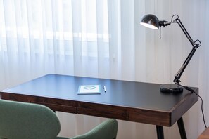 A wooden desk with a black desk lamp, a notebook, and a pen.