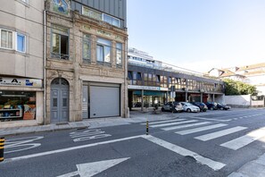 A street view with a building featuring a closed garage door, a row of parked cars, and a clear sky. - Feel Corporate Housing Marqu s V (Porto)