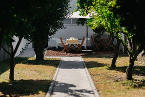 Un sendero que lleva a una mesa bajo un árbol, con un edificio al fondo.