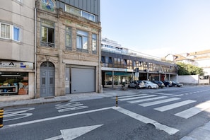 A street view with a building featuring a closed garage door, a medical office, and parked cars. - Feel Corporate Housing Marqu s II (Porto)