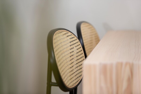 A close-up of a chair with a woven seat and backrest, positioned next to a table with a light-colored tablecloth.