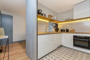 Une cuisine moderne avec des armoires blanches, un plan de travail en bois et un four encastré.