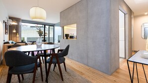Een moderne eetruimte met een ronde tafel, donkere stoelen en een lamp erboven.