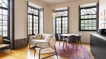 Una habitación con sofá, sillas, una mesa de comedor y una zona de cocina.