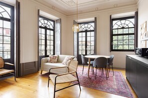A room with a sofa, chairs, a dining table, and a kitchen area.