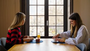 Two people sitting at a wooden table with a bowl and a glass of orange juice. - Feel Porto Antique Poveiros Flat II (Porto)