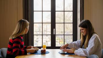 Dos personas sentadas en una mesa de madera con un tazón y un vaso de jugo de naranja.