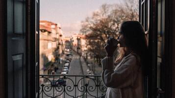 Una persona de pie junto a una ventana con vista a una calle y edificios.