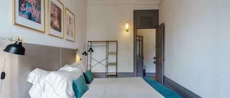 A hotel room with a bed, a bedside table, a lamp, and framed pictures on the wall.