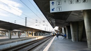 Un quai de gare avec des voies ferrées en hauteur et un panneau indiquant les directions vers les lignes 2 et 1.