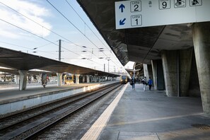 Un quai de gare avec des voies ferrées en hauteur et un panneau indiquant les directions vers les lignes 2 et 1.