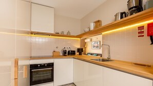 Eine moderne Küche mit weißen Schränken, einem Einbauofen, einer Spüle und einer Holz Arbeitsplatte.