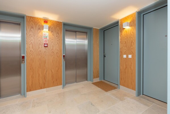 An elevator area with four elevators, wooden paneling on the walls, and a tiled floor. - Feel Corporate Housing Campanh 03 (Porto)