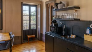 Una cocina compacta con cafetera, un lavamanos y un pequeño comedor con un banco.