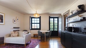 A modern kitchen with a dining area, featuring a sofa, rug, and a pendant light. - Feel Porto Antique Poveiros Flat III (Porto)