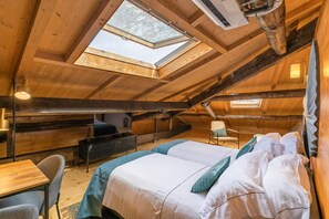 Cozy attic retreat with a sloped ceiling, skylight, and comfortable seating area.