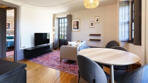 Una sala de estar moderna con un televisor de pantalla plana, una mesa de comedor redonda y un sofá.