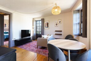 Uma sala de estar moderna com televisão de tela plana, uma mesa de jantar redonda e um sofá.
