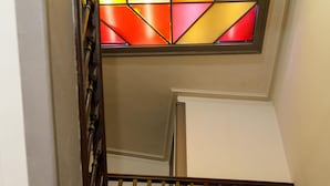 Una escalera de madera con un vitral en lo alto.
