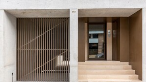 A building entrance with a metal gate, a staircase, and a door with an elevator control panel. - Feel Corporate Housing Campanh 05 (Porto)
