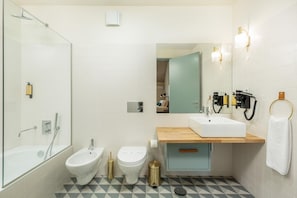 A modern bathroom with a shower, bidet, toilet, and sink.