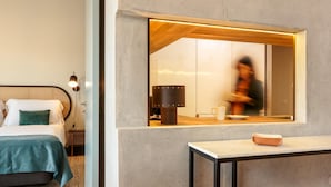 A modern hotel room with a bed, bedside table, and a large mirror reflecting a person in the kitchen area. - Feel Corporate Housing Campanh 05 (Porto)