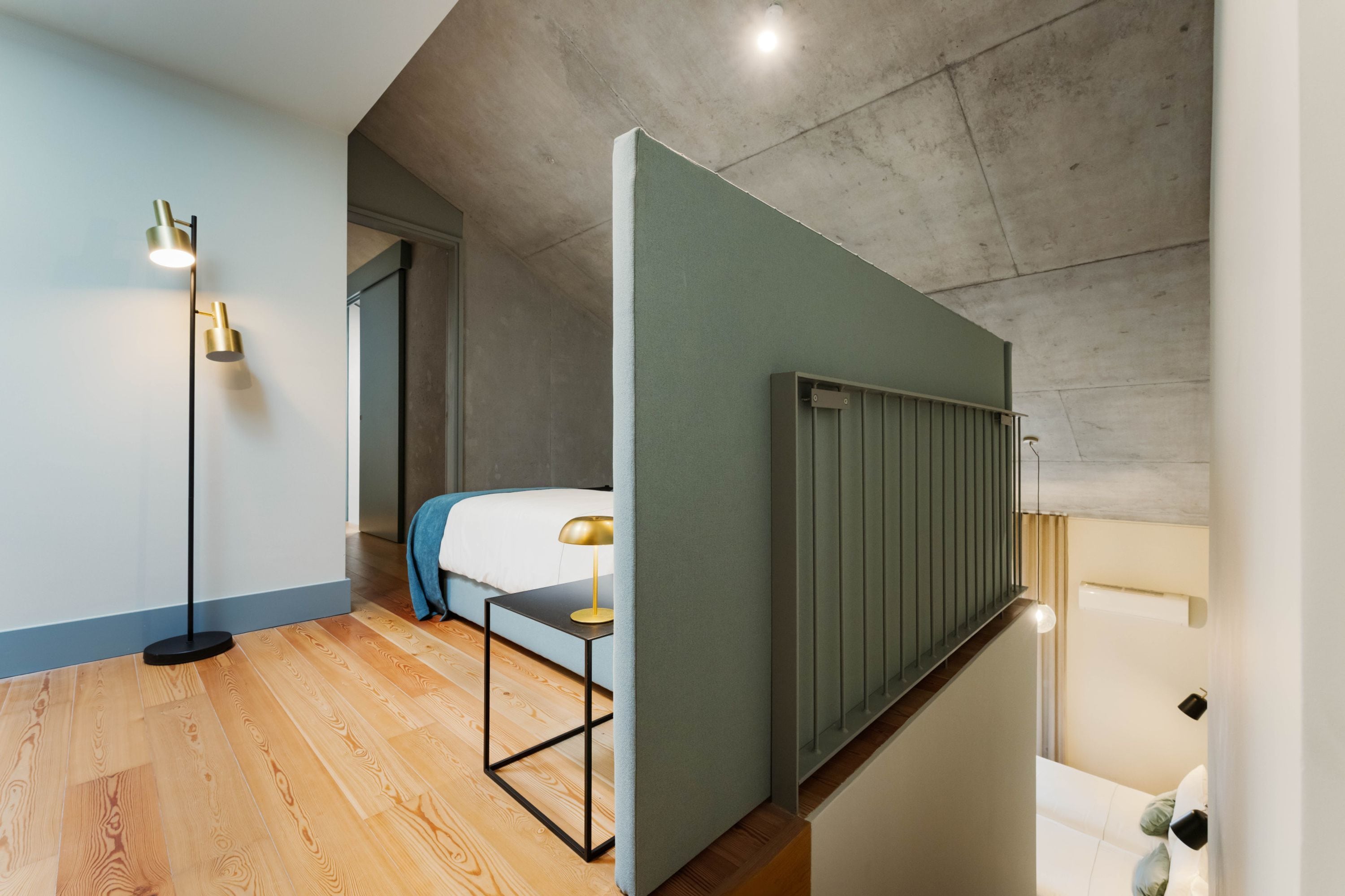 A modern bedroom with a bed, a standing lamp, and a small table.