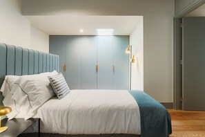 Une chambre à coucher comprenant un lit, une table de chevet, une lampe, une armoire et un luminaire au plafond.