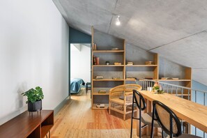 Une pièce de style loft avec une table à manger en bois, des chaises, une bibliothèque et une plante en pot.